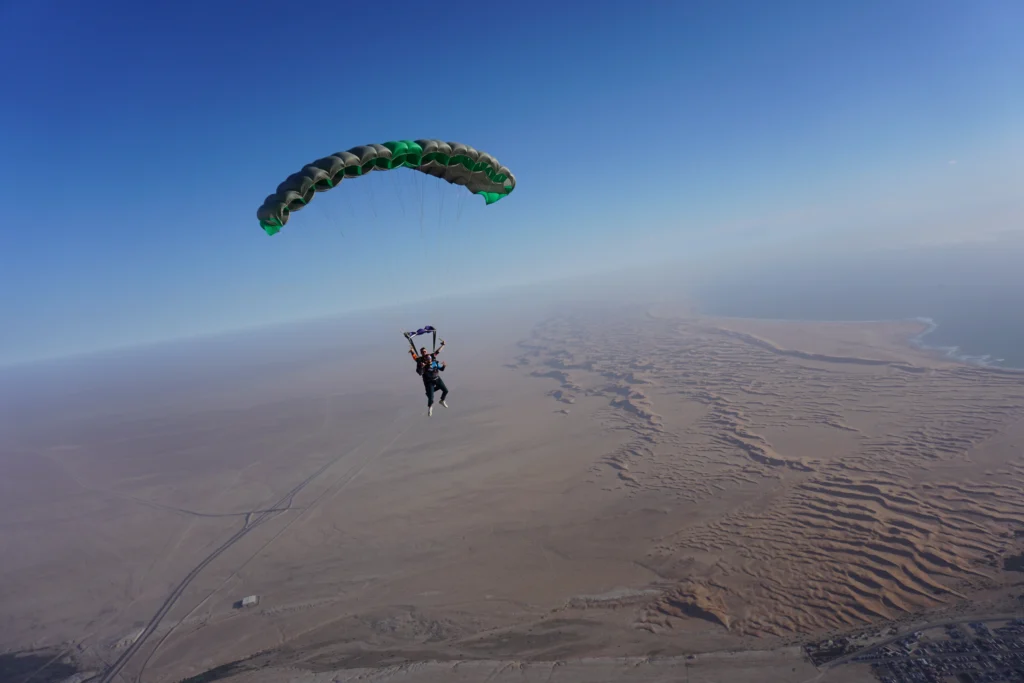 Tandem parachute glides above sweeping dunes near the Atlantic coast skydive zone