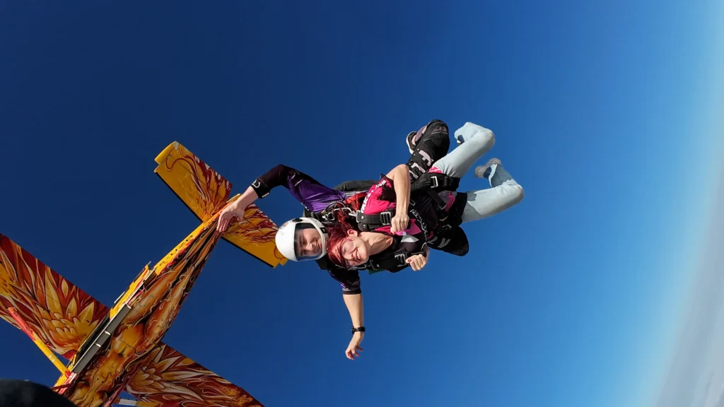 Tandem skydivers freefall beside the flame-painted jump plane, skydiving Namibia