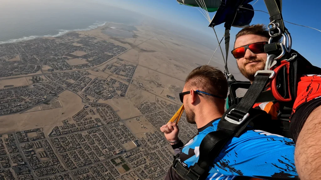 Tandem passenger steers the canopy under instruction high above Swakopmund and the Atlantic coast