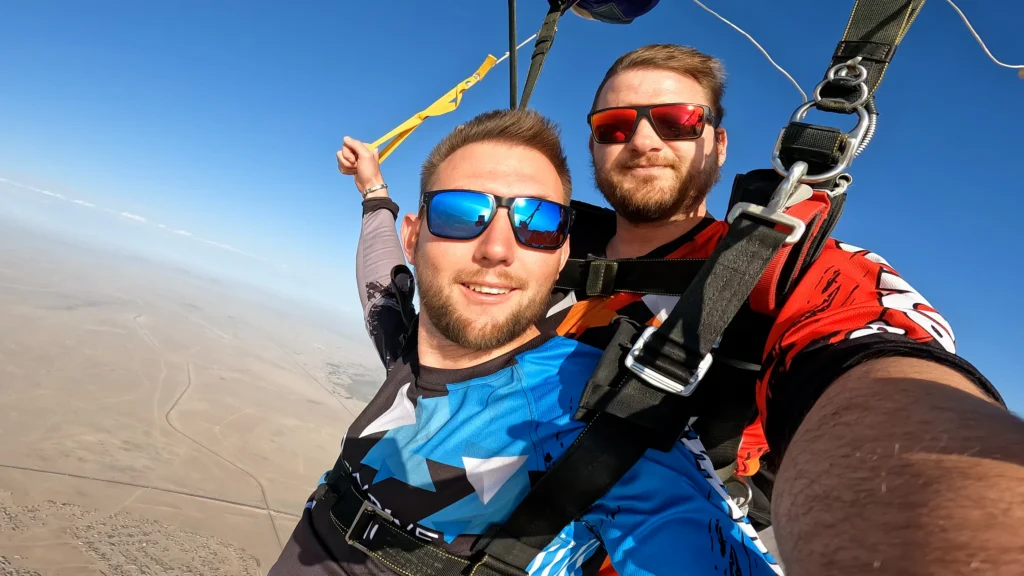 Two skydivers take a selfie under an open canopy above Swakopmund dunes