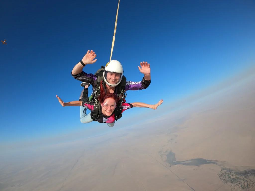 Tandem instructor and passenger wave during freefall above the desert, tandem skydive Swakopmund