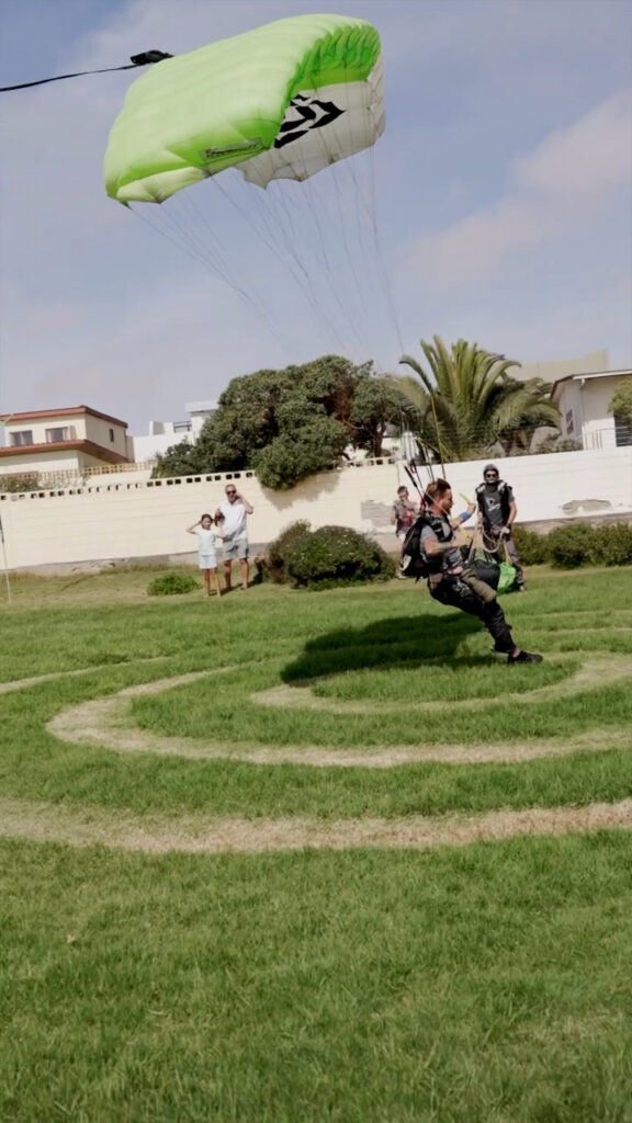Skydiver lands precisely on the grass bullseye target as spectators watch, skydiving Namibia