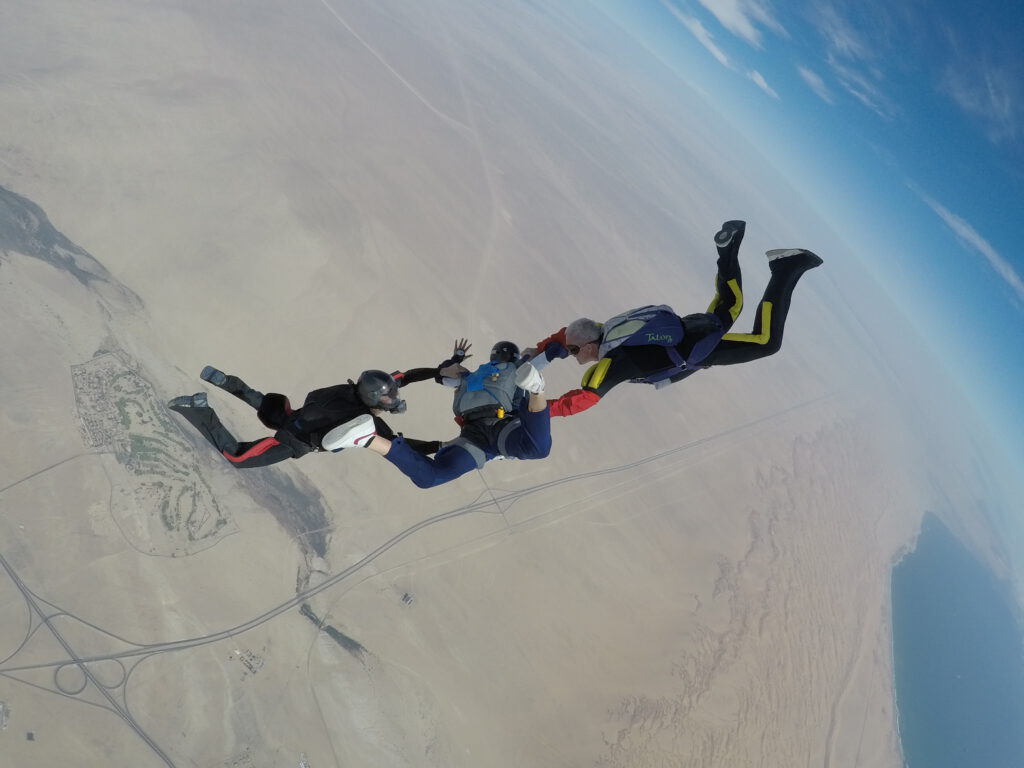 Two instructors hold an AFF student in freefall high above the Namib desert near Swakopmund