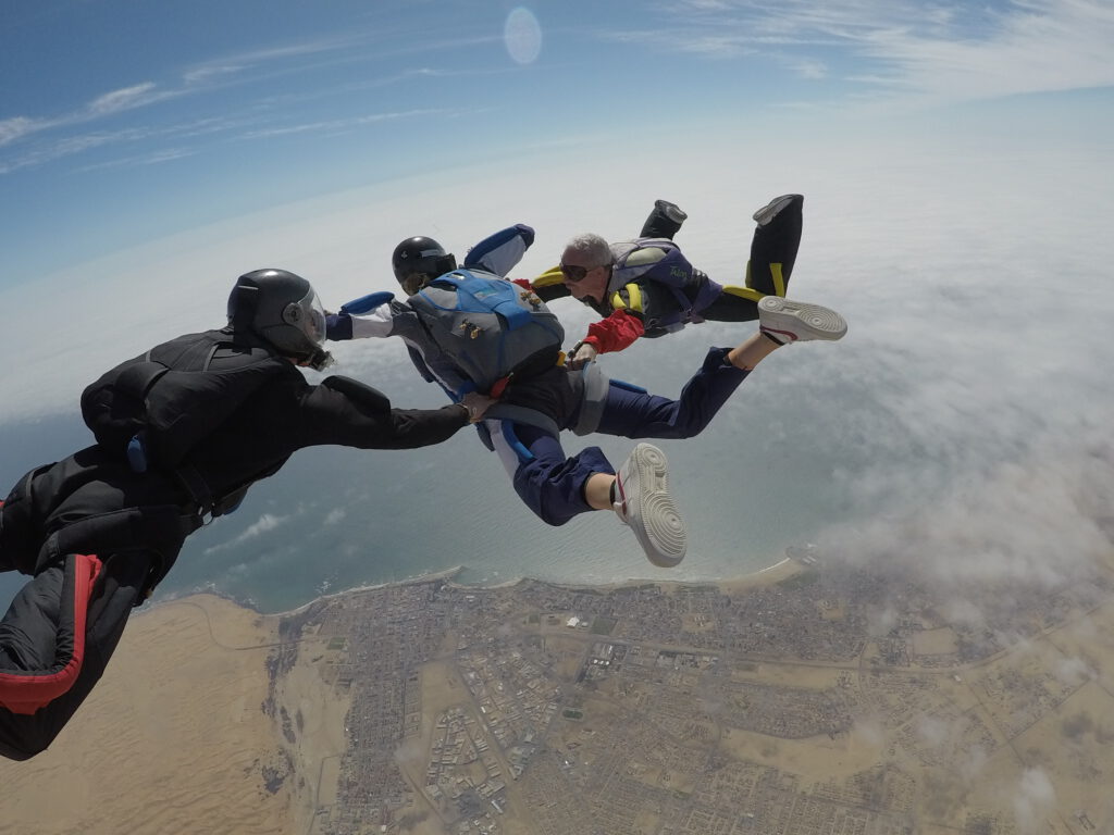 Two instructors hold an AFF student in freefall high above Swakopmund town and the Atlantic coast
