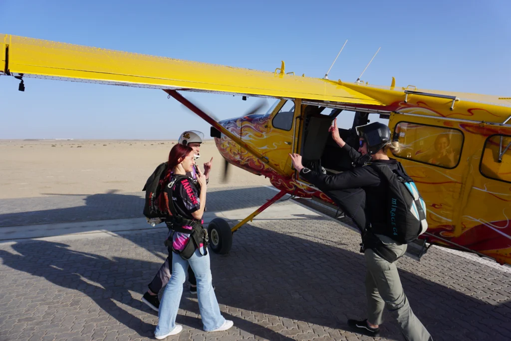Tandem instructor and passenger with camera skydiver filming as they prepare to board the skydive plane “The Angel” in Swakopmund