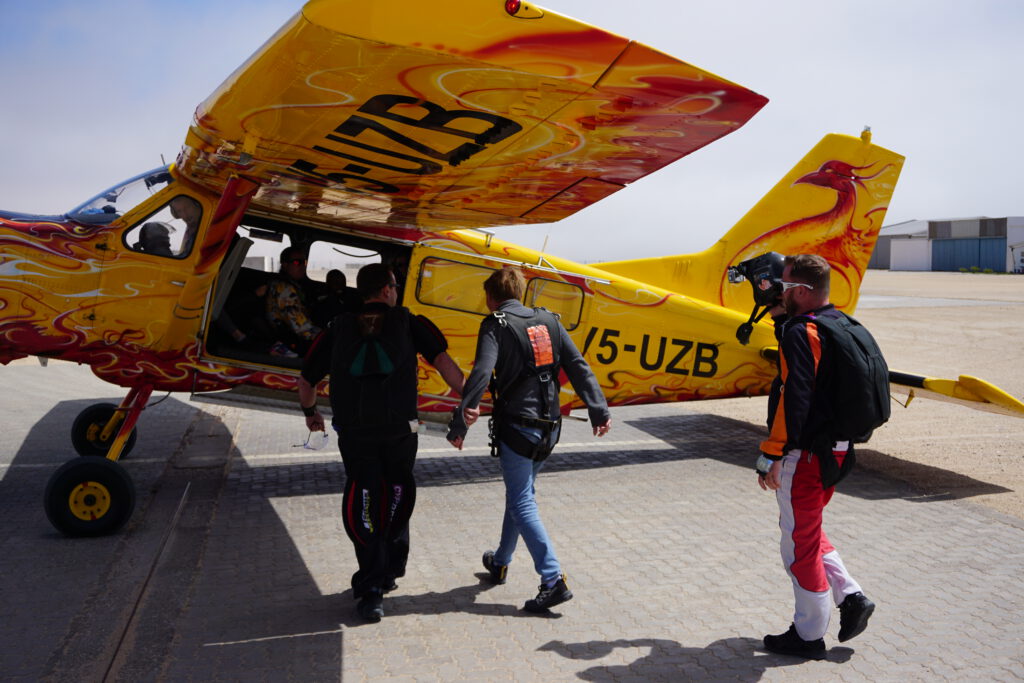 Instructors and passengers walk toward the plane before a tandem skydive in Swakopmund