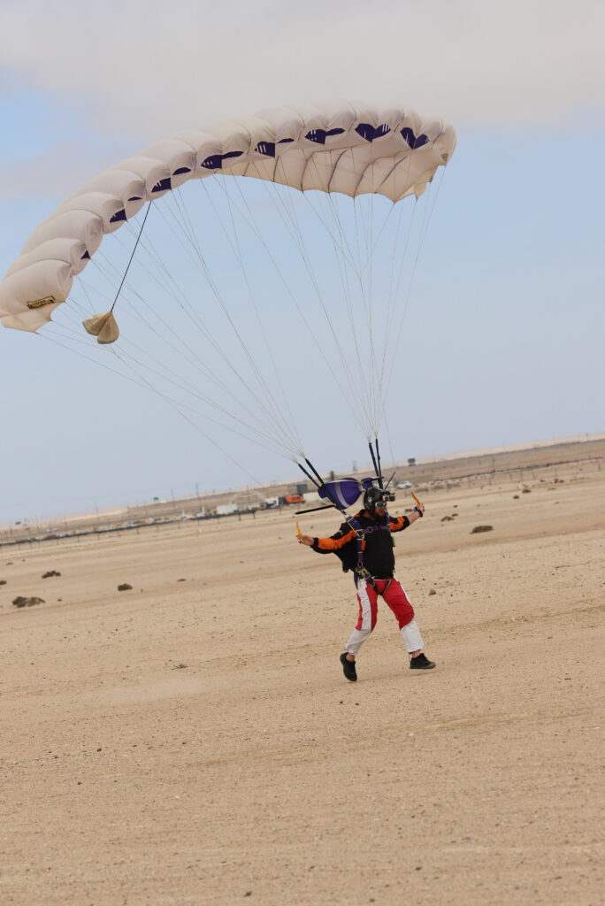 Camera skydiver standing on the desert after landing with parachute canopy still open in Swakopmund