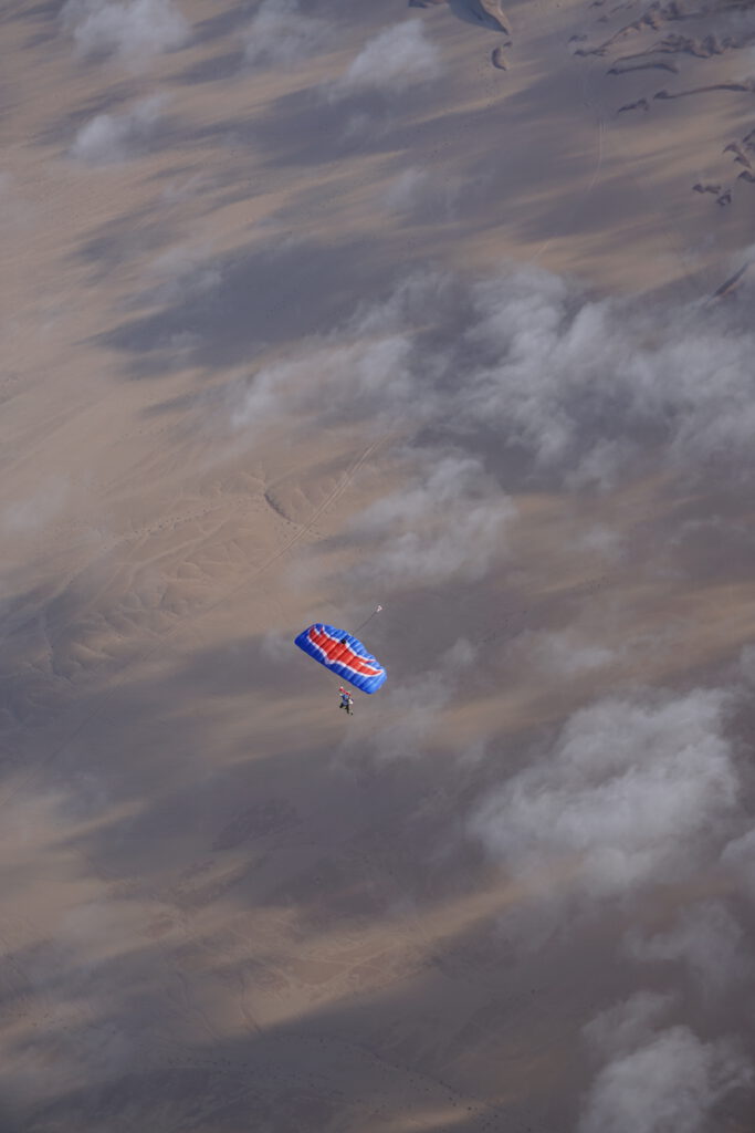 Parachutist glides above drifting fog over the Swakopmund dunes landscape