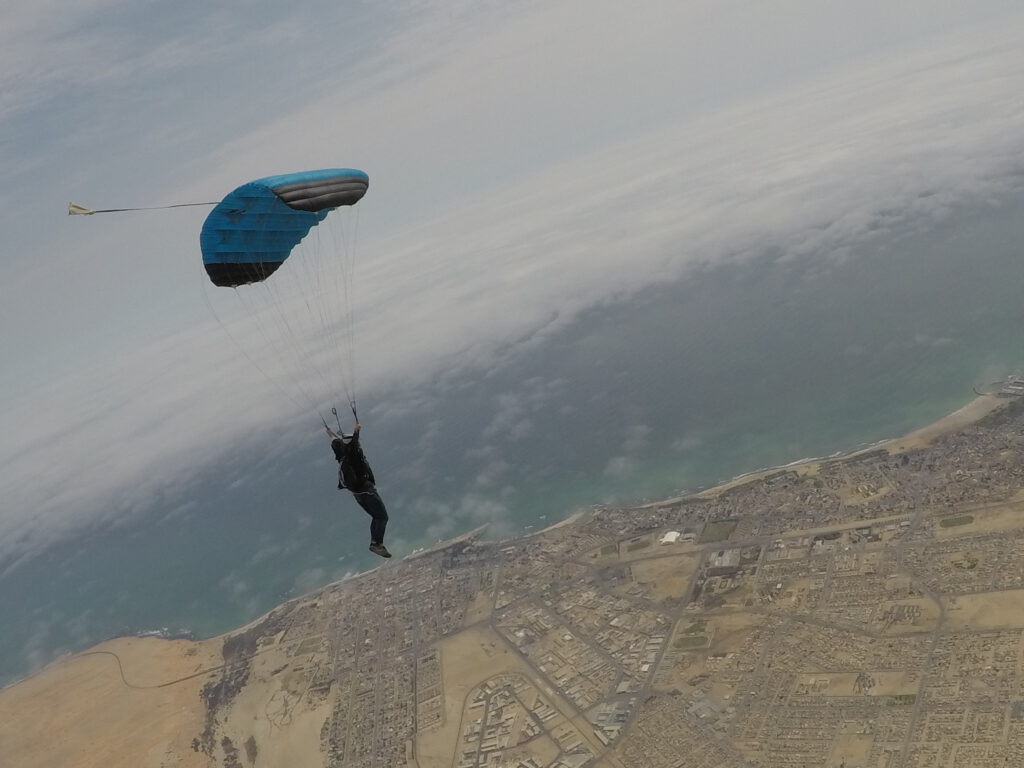 Skydiver glides under a blue canopy above the city on an Atlantic coast skydive