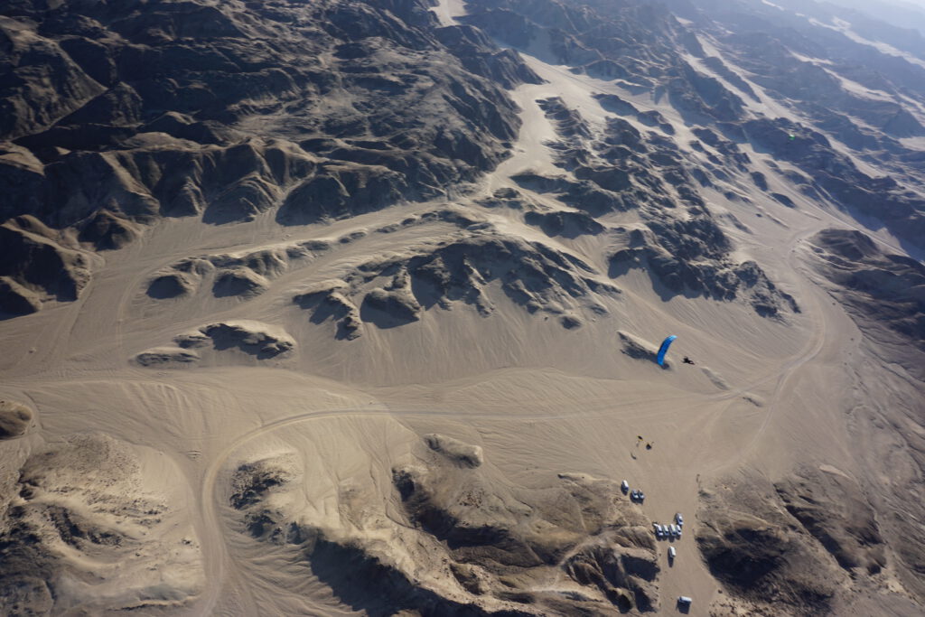 Skydiver descends under a blue canopy above the Moon Landscape near Swakopmund, Namibia