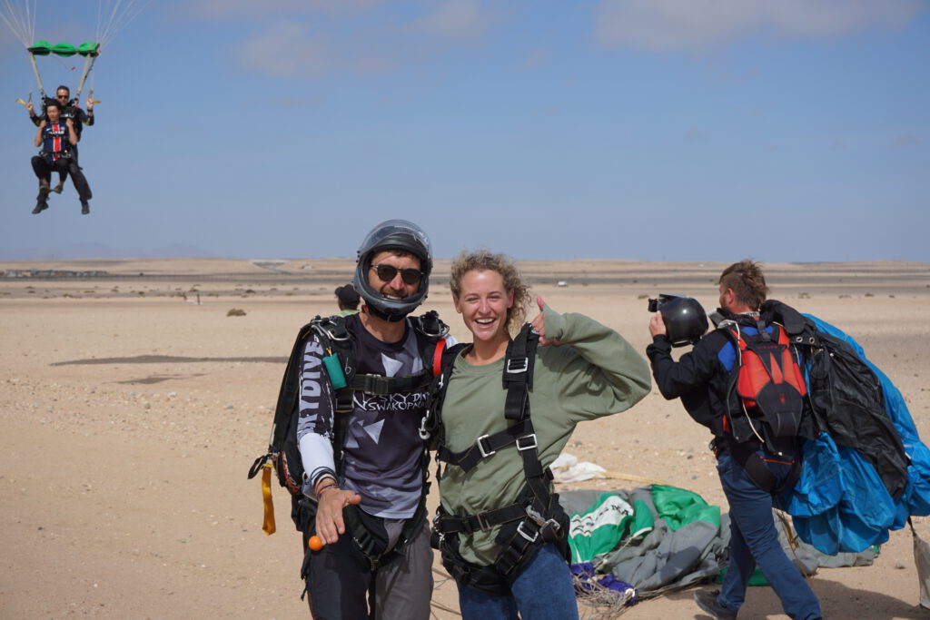 Instructor and passenger celebrate skydiving Namibia landing as another tandem descends