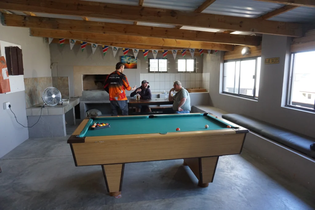 Men chat around a pool table inside the skydive center's clubhouse lounge