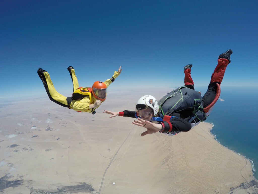 Skydiver instructor and student descending over the Swakopmund dunes where they meet the ocean