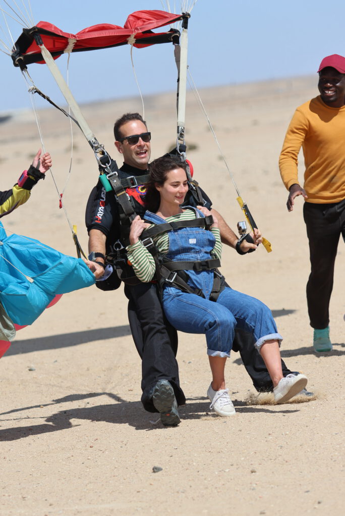 Instructor and passenger slide in to land as ground crew run alongside in the Namib desert