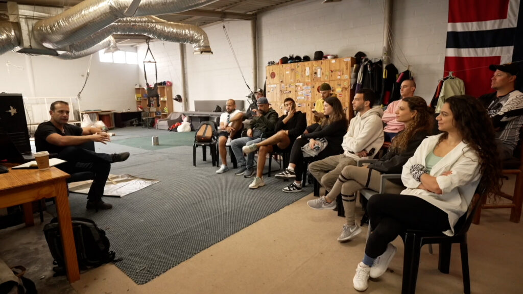 Instructor addresses a seated group of skydiving students in class