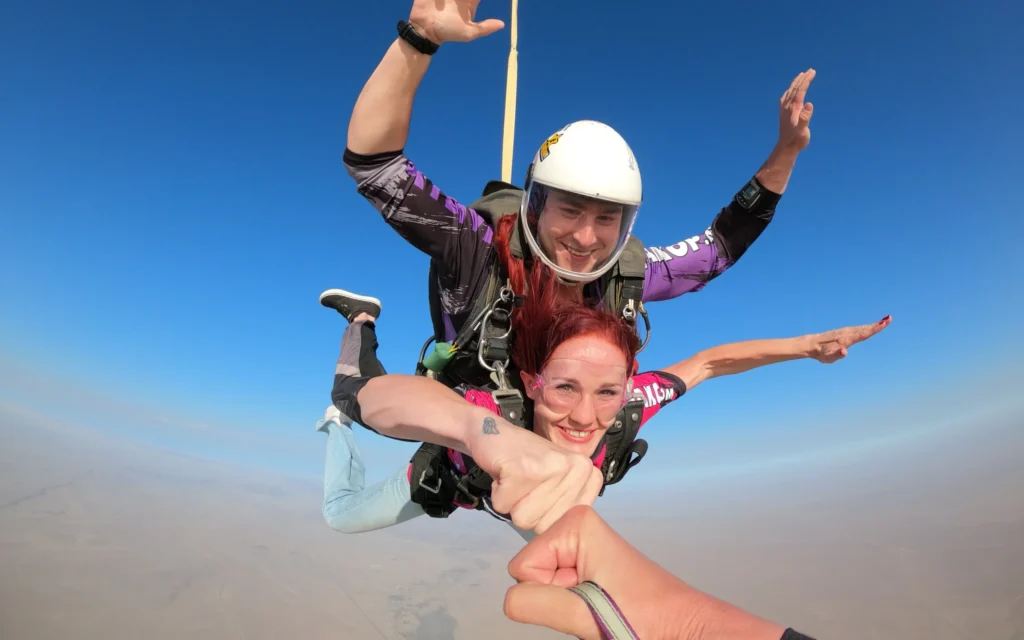Red-haired passenger fist bumps the camera during a skydiving Namibia freefall