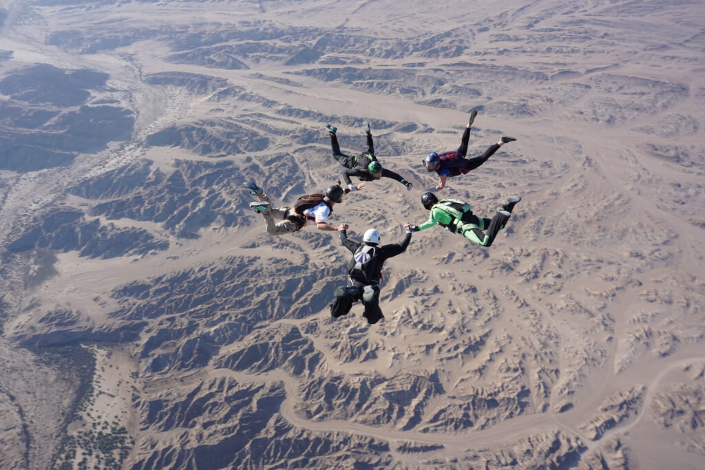 Formation of professional skydivers flying in freefall above Namibia’s Moon Landscape during the Euroinvasion skydiving event