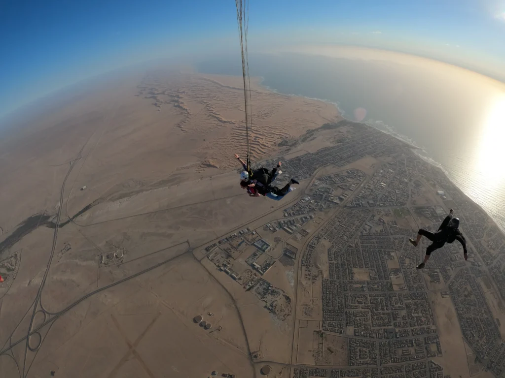Tandem pair and camera flyer free fall above the Swakopmund dunes and coastline