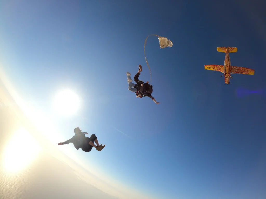 Two skydivers free-fall beside the Angel plane on a skydive Namibia coast jump
