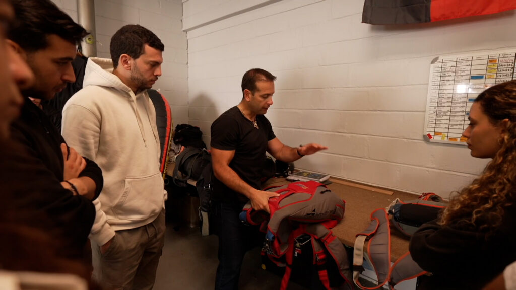 Instructor shows an AFF student the parachute harness and container during equipment training in Swakopmund