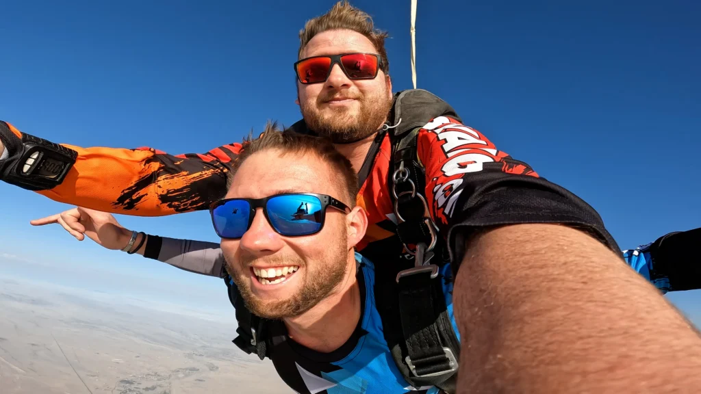 Two skydivers grin for a selfie during a high-altitude skydiving Namibia freefall
