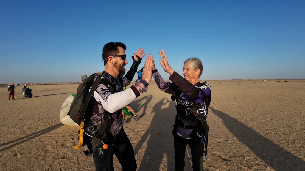 Tandem skydive Swakopmund instructor high-fives an elderly passenger in the evening sun
