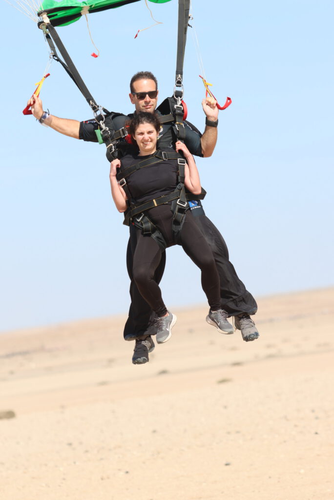 Tandem pair descends under an open canopy just before landing on the Namib sand