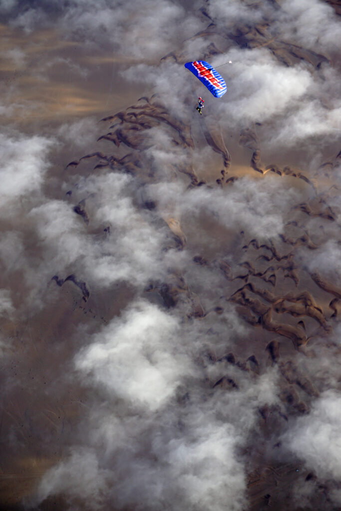 Parachutist descends through drifting fog above the rugged Swakopmund dunes
