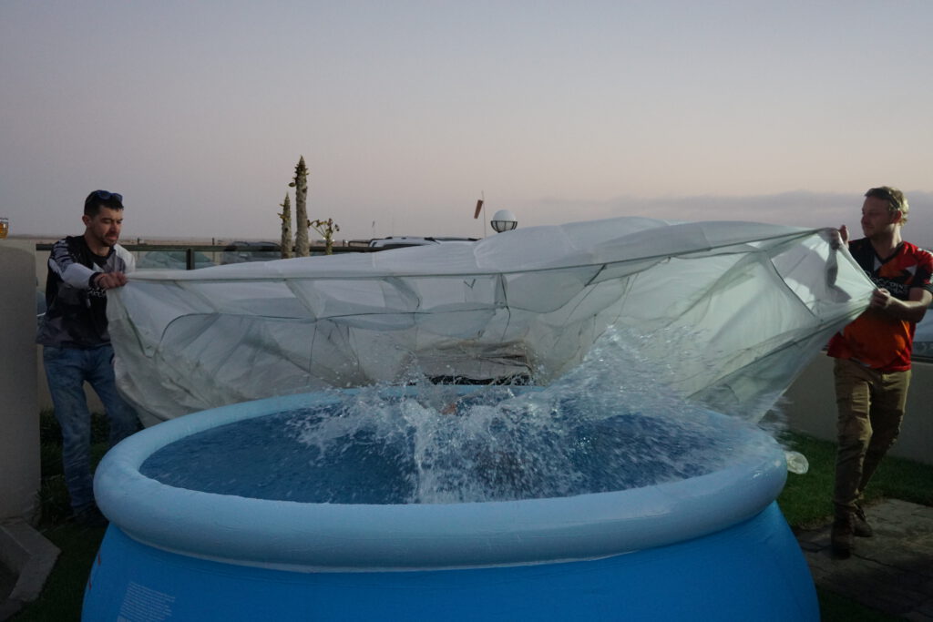 Skydiving Namibia crew hold a parachute canopy above a splashing pool