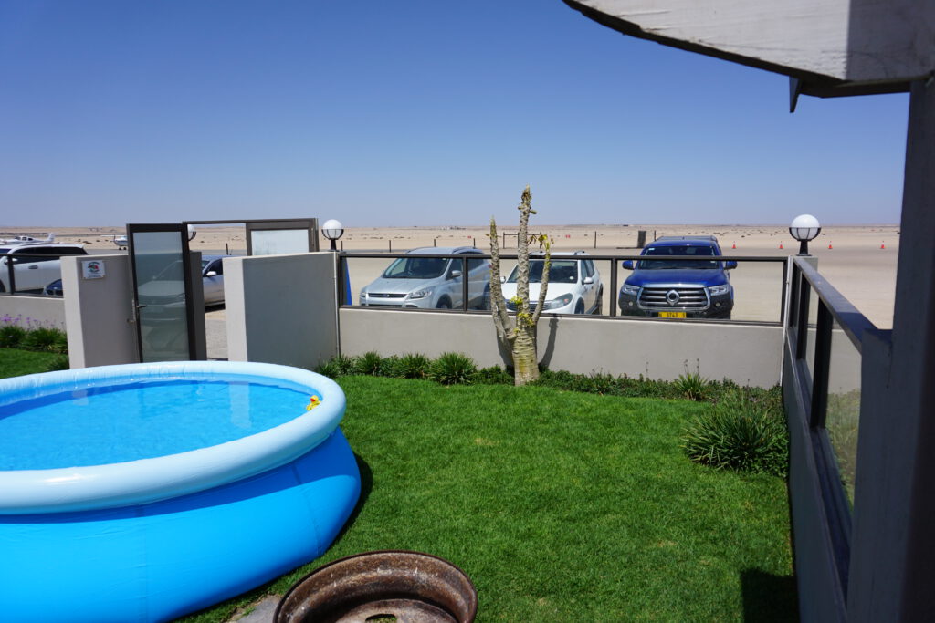 Inflatable pool on a lawn with the desert airfield visible beyond the fence
