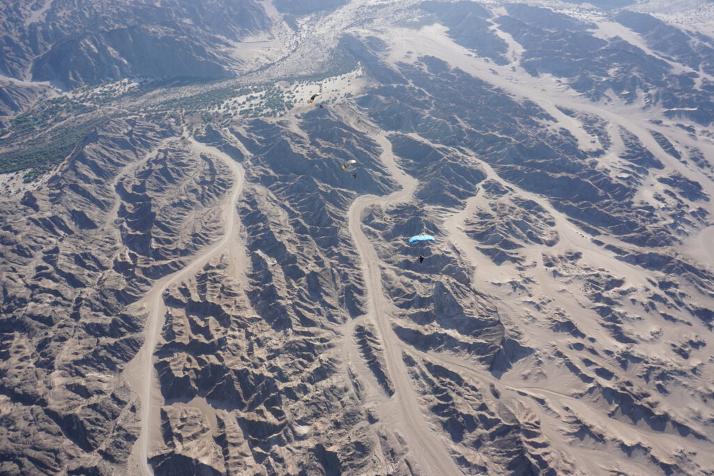 Professional skydivers flying under open canopies above Namibia’s Moon Landscape during the Euroinvasion skydiving event