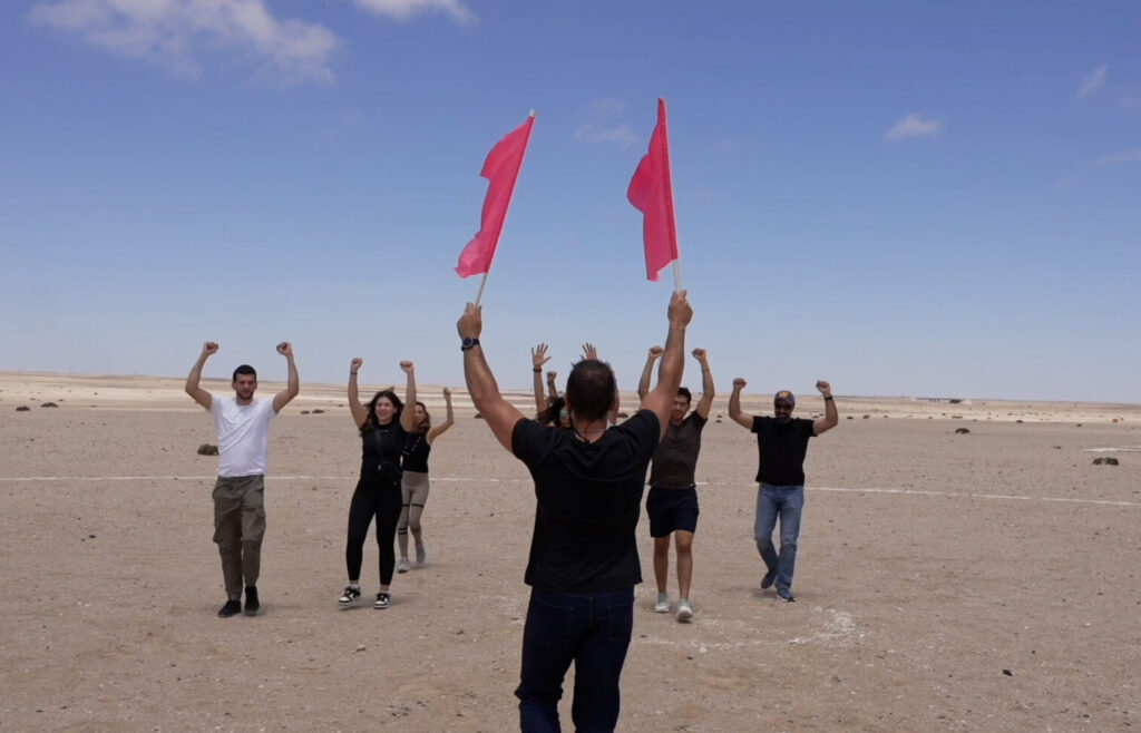 Instructor waves signal flags as AFF students practice responding during landing training near Swakopmund