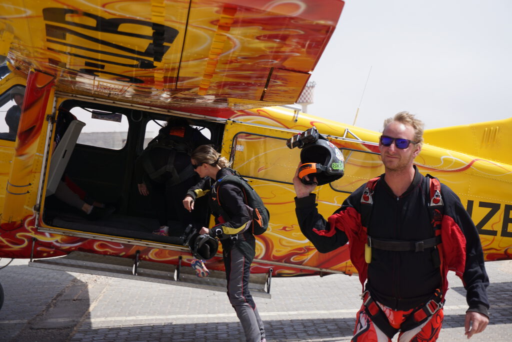 Skydivers carry their helmets while boarding the plane for a skydiving Namibia flight