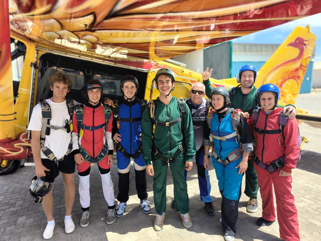 Group poses in front of the plane during a skydiving Namibia excursion