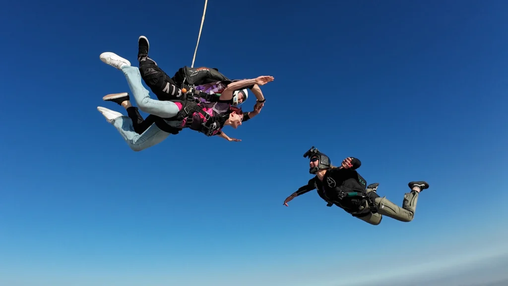 A tandem skydive Swakopmund free fall with camera man against a clear blue sky