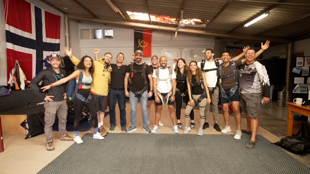 Group of skydivers in harnesses cheer together for a team photo
