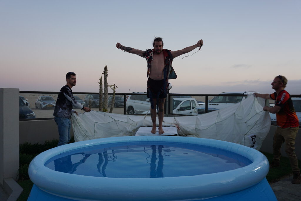 Shirtless jumper spreads his arms while leaping into a celebration pool