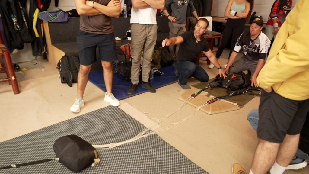 Instructor explains parachute rig and deployment lines to AFF students during ground school in Swakopmund